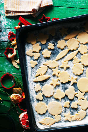 Process of baking cookies at home. Fresh dough ready for baking on rustic green wooden background. Dough ingredients and decorations aroundの写真素材