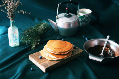 Sweet fresh poppy seed pancakes with chocolate fondant and decorated with fresh raspberries on a wooden board on a kitchen table with a tablecloth covering of blue, decorated with pine branches.の写真素材