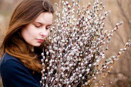Portrait of a beautiful young girl with a huge armful of willow in hands. Young woman gardening.の写真素材