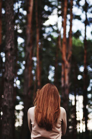 Rear view. Retro toned portrait of young girl in summer field from back. Young woman standing on a...