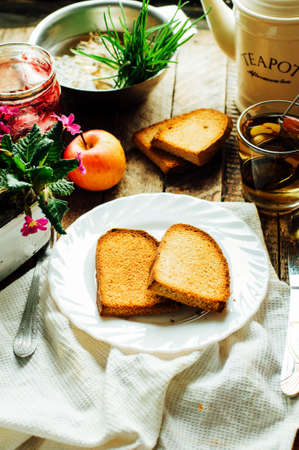 Toast with jam and cup of tea on old wooden table. Delicious toast with jam on table close-up.の写真素材