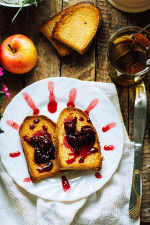 Toast with jam and cup of tea on old wooden table. Delicious toast with jam on table close-up.の写真素材