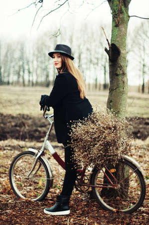 Beautiful young girl with long straight hair, light make-up in a stylish trendy business suit standing outdoors in a parkの写真素材