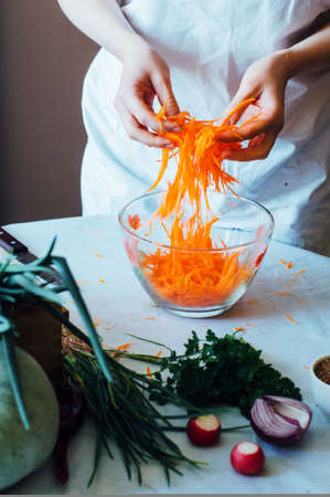 Woman on kitchen cuts vegetables for salad. Dieting and detox drink concept. Country  style. Ladies hand cut vegetable, ready to prepare healthy salad. carrots, cabbage, radishes, peppers, parsleyの写真素材