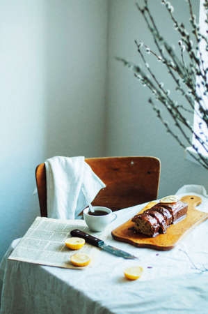 Cupcake for breakfast . Rustic dark styling. With retro filter effect. Homemade fresh-baked milk cake on the white tablecloth at a window. Country white kitchenの写真素材