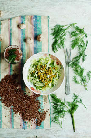 Fresh organic vegetables. Healthy herbs from garden. Fresh organic vegetables and herbs. Preparing salad with fresh cabbage, fennel, flax seeds, canned peas, seasoned with lemon juiceの写真素材