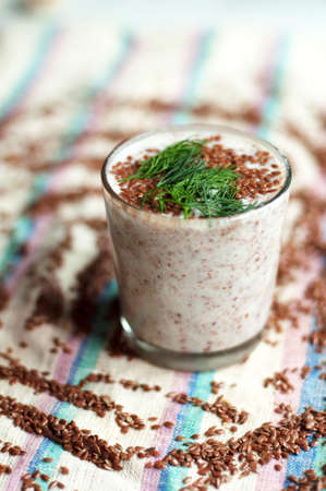 Glass of yogurt with crushed flax seeds  on a white background. Cocktail from kefir  in a transparent glass. Fresh homemade Kefir shake with flax seeds for a breakfast. Bio homemade dairy beverage.の写真素材
