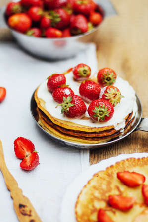 Strawberries and whipped cream  for dessert. Pancakes with  strawberries and sour cream. Stack of pancakes with fresh strawberry and balsamic glase in frying pan on wooden table. Rustic styleの写真素材