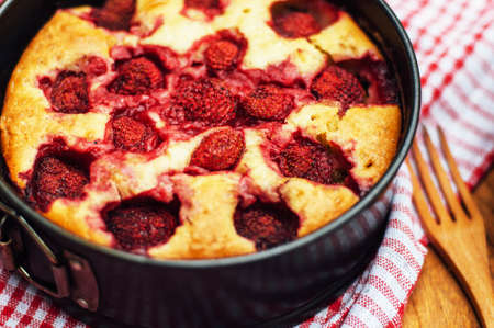 Serving homemade strawberry cake or pie on wooden rustic table. Tart with fresh strawberry on wooden background. Strawberry tart  with icing sugar and whole fruits onwith cooking utensils. Rustic stylの写真素材