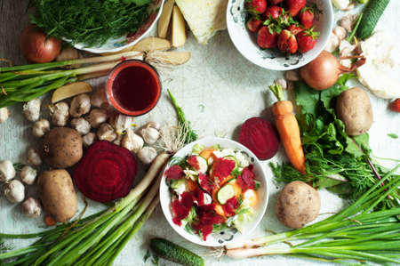 Orange and green veggies and roots composition on a dark slate table. Carrots, onions, dandelion,...