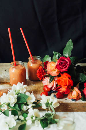 Hands makes strawberry smoothies in wooden table . Fresh strawberry smoothies fruit. Recipe carrot-strawberry smoothie. Action. Rustic dark style. Clean eating breakfast concept.の写真素材