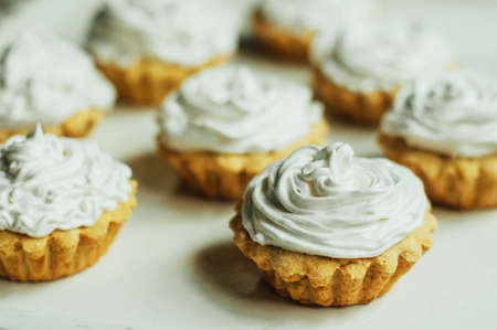Beautiful chocolate cupcakes with white protein cream and cherry. Vanilla cupcakes with  cream frosting and a cherry on top. Cherry Cupcake Shot on wooden table. Ripe red cherries and currant muffinの写真素材