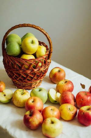 Apples  on white table. Sweet apples on table on bright background. basket with ripe tasty apples on white table. White table full of freshly harvested red apples with a halved apple on displayの写真素材