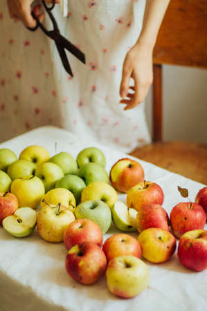 Apples  on white table. Sweet apples on table on bright background. basket with ripe tasty apples on white table. White table full of freshly harvested red apples with a halved apple on displayの写真素材