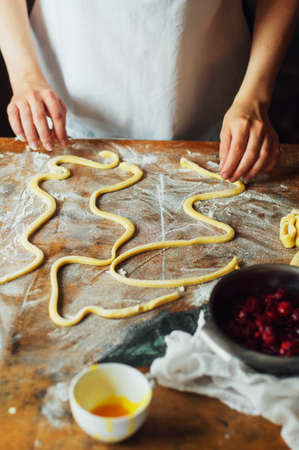 Ingredients for baking cake stuffed with fresh cherry pie. Female preparing cherry pie. Rustic dark style. See series recipe step on step. Womans hands. Recipe for homemade pie on short pastryの写真素材