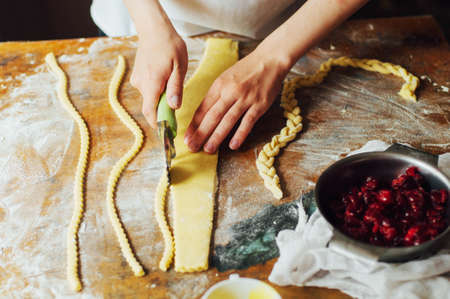 Ingredients for baking cake stuffed with fresh cherry pie. Female preparing cherry pie. Rustic dark style. See series recipe step on step. Womans hands. Recipe for homemade pie on short pastryの写真素材