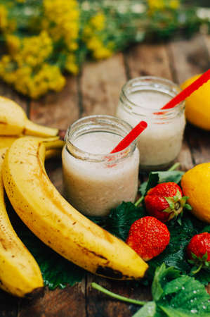 Fruit Smoothies. banana smoothies with milk. Banana Smoothie on a wooden table. Healthy breakfast: banana smoothie with oatmeal. Banana smoothie in glass with fresh fruits on wooden backgroundの写真素材