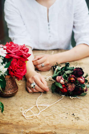 Gardener doing gardening work at a table rustic. Working in the garden, close up of the hands of a woman cares flowers carnations. Womans hands. Garden tools with flowers.の写真素材