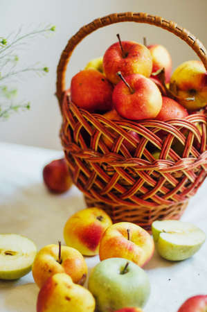 Apples  on white table. Sweet apples on table on bright background. basket with ripe tasty apples on white table. White table full of freshly harvested red apples with a halved apple on displayの写真素材