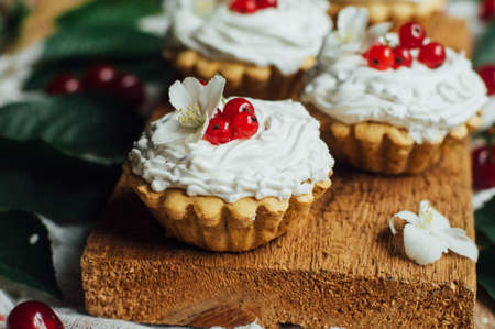 Beautiful chocolate cupcakes with white protein cream and cherry. Vanilla cupcakes with  cream frosting and a cherry on top. Cherry Cupcake Shot on wooden table. Ripe red cherries and currant muffinの写真素材