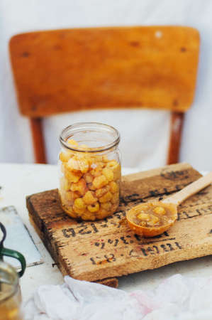 raspberries jam. Female hand making jam, on a rustic white table. Country  styling. Cooking...