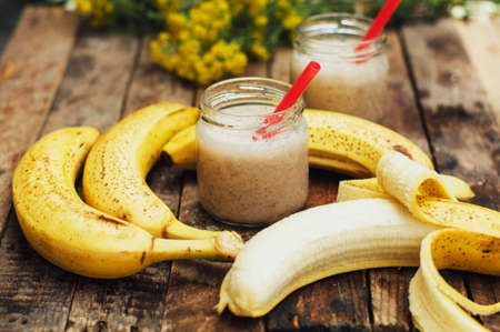Fruit Smoothies. banana smoothies with milk. Banana Smoothie on a wooden table. Healthy breakfast: banana smoothie with oatmeal. Banana smoothie in glass with fresh fruits on wooden backgroundの写真素材