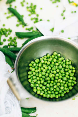 Woman podding fresh peas in the kitchen. Woman podding fresh peas in the kitchen. 
Fresh peas and pods. Large amount of fresh organic pea pods.の写真素材