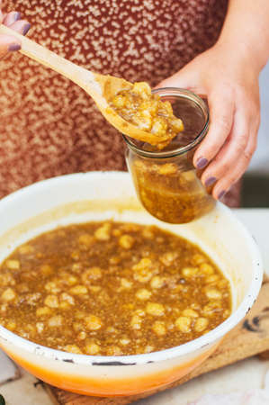 raspberries jam. Female hand making jam, on a rustic white table. Country  styling. Cooking delicious raspberries jam in kitchen. Prepared homemade orange raspberries jam over on kitchen. Rustic styleの写真素材