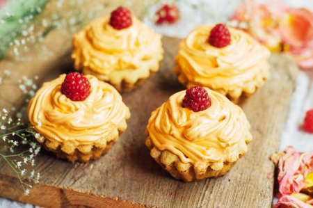 cupcakes on wooden table. Homemade decorated muffins on the table. sweet table full of homemade desserts.  muffins with rasberries frosting. Homemade muffins with wild rasberries and protein creamの写真素材