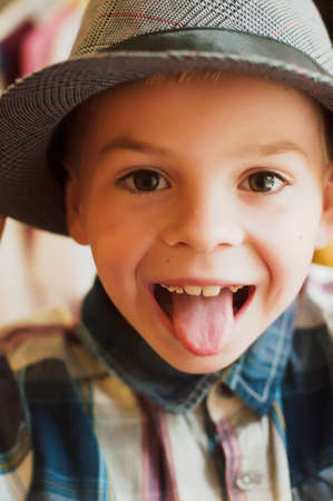Child's happy face . Portrait of a Cute Kid.  little boy with short blond hair and brown yeas. Beautiful little boy seven years posing with a hat and denim shirt. Smailing boyの写真素材