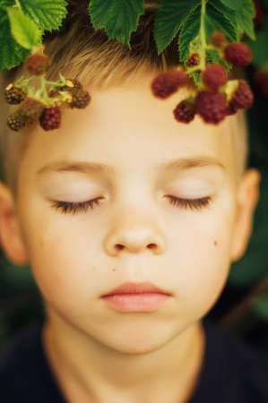 Portrait of an Adorable Boy in outdoor.  Small handsome boy 7 years old posing in the garden outdoors.  Summer portrait of a young boy with brown eyes and blond hairの写真素材