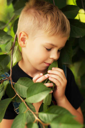 Portrait of smiling seven year old boy. Seven year old boy  with brown eyes and blond hair. Young boy in a black T-shirt and denim overalls outdoor.  Boy's portrait.の写真素材