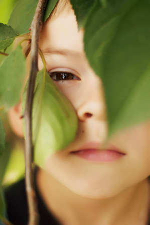 Portrait of smiling seven year old boy. Seven year old boy  with brown eyes and blond hair. Young boy in a black T-shirt and denim overalls outdoor.  Boy's portrait.の写真素材
