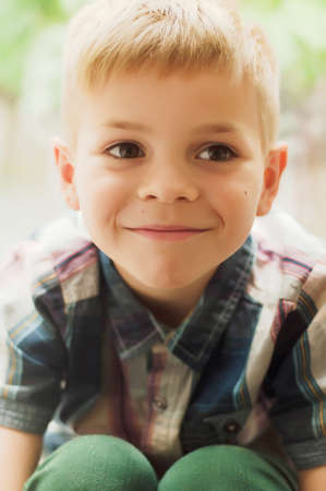 Child's happy face . Portrait of a Cute Kid.  little boy with short blond hair and brown yeas. Beautiful little boy seven years posing with a hat and denim shirt. Smailing boyの写真素材