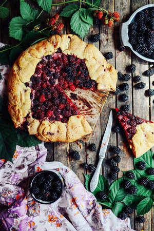 freshly baked berry pie. Blackberries pie with a slice missing. Berry pie preparation.   pie in summer with fresh picked blackberries.の写真素材