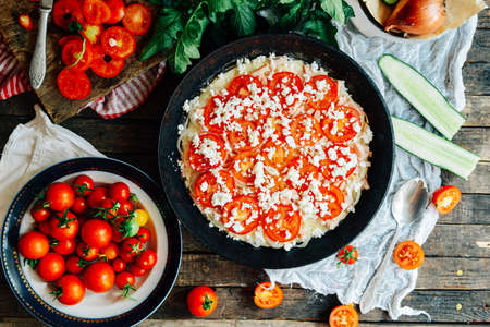 Veggie pizza. Pizza with tomatoes, shallot and fresh herbs. Cherry Tomato Wood Fired Pizza. Homemade margarita pizza sitting on a wooden cutting board. Pizza with pesto, mozzarella and cherry tomatoesの写真素材