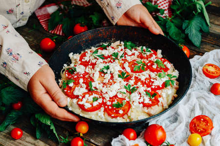 Veggie pizza. Pizza with tomatoes, shallot and fresh herbs. Cherry Tomato Wood Fired Pizza. Homemade margarita pizza sitting on a wooden cutting board. Pizza with pesto, mozzarella and cherry tomatoesの写真素材