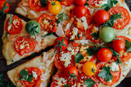 Veggie pizza. Pizza with tomatoes, shallot and fresh herbs. Cherry Tomato Wood Fired Pizza. Homemade margarita pizza sitting on a wooden cutting board. Pizza with pesto, mozzarella and cherry tomatoesの写真素材