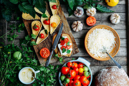 Dewberry mini tart on the wooden table. Delicious homemade tartlets with grated processed cheese and garlic garnished with fresh red tomatoes.  See series.の写真素材