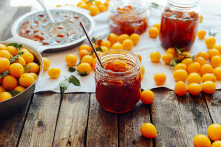 plums jam in a small cup. Homemade spicy mirabelle, greengage plum chutney in jars. Pouring plum jam into jarsの写真素材