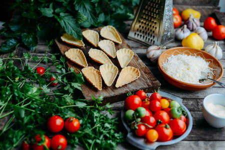 Dewberry mini tart on the wooden table. Delicious homemade tartlets with grated processed cheese and garlic garnished with fresh red tomatoes.  See series.の写真素材