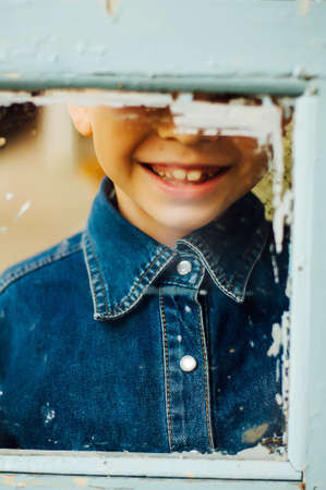 Child's happy face . Portrait of a Cute Kid.  little boy with short blond hair and brown yeas. Beautiful little boy seven years posing with a hat and denim shirt. Smailing boyの写真素材