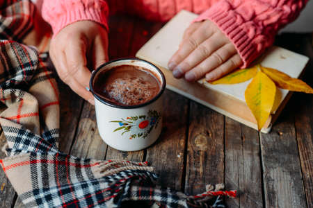 Woman holding cup of hot chocolate. Hot Chocolate in wooden table.  Woman having a cup of coffe. Rose hip tea and fresh rose hips.Autumn composition.の写真素材