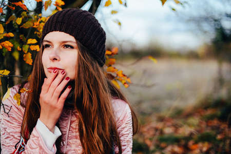 Closeup outdoors portrait of gorgeous young  Caucasian woman.  outdoors in park on sunny fall day. colorful autumn portrait. Portrait of a beautiful, dreamy  girl with long  hair. in autumn parkの写真素材