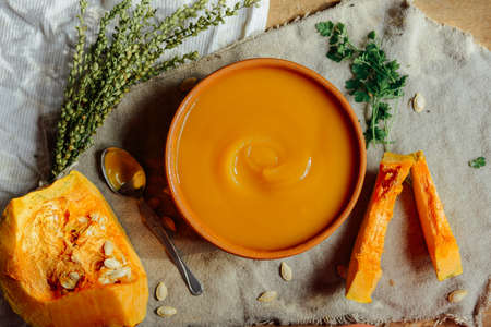 Pumpkin porridge and pumpkins on black wooden table. Plate pumpkin porridge is on a brown wooden table. pumpkin porridge. Millet porridge with pumpkin.の写真素材