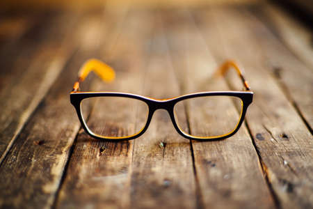 glasses  lie on the dark wooden table.   Black orange  glasses on wooden table. Office workplace with glasses on wood table. Glasses with orange rim. Orange Case for storage points.の写真素材