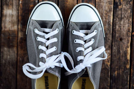 Ukraine, Kiev, October 30, 2016: crey Converse shoes on wooden planks. 
crey sneakers on wooden background with copy space. Top view. sneakers on wooden deck.のeditorial素材