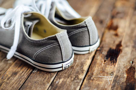 Ukraine, Kiev, October 30, 2016: crey Converse shoes on wooden planks. 
crey sneakers on wooden background with copy space. Top view. sneakers on wooden deck.のeditorial素材