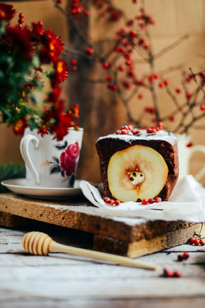 Rustic open apple and pear pie in rustic table setting. Baked pears wrapped in  pastry. Fall colours. A delicious chocolate cake with pear filling berries decorationの写真素材