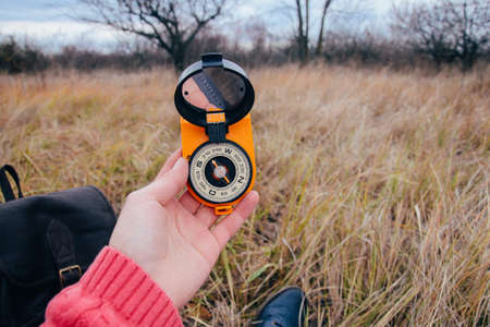 Woman traveler sitting on autumn nature background, point of view shot. Unrecognizable young girl on a hike in autumn forest with a compass in hand. Relax in a nature. Traveler resting in the natureの写真素材